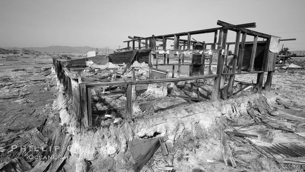 Bombay Beach, lies alongside and below the flood level of the Salton Sea, so that it floods occasionally when the Salton Sea rises.  A part of Bombay Beach is composed of derelict old trailer homes, shacks and wharfs, slowly sinking in the mud and salt, Imperial County, California