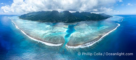 Barrier Reef around Moorea Island, French Polynesia. Nu'urua and Iumaru communities along the coast. The outer reef slope is seen adjacent to deep blue oceanic water with white waves breaking against the reef edge. Next, a wide shallow reef flat occurs dotted with coral bommies. Inside of that, a shallow protected lagoon is formed against the island.  Tall, rugged, eroded mountains are seen hinting at the age of the ancient volcano that originally formed the island and that is now sinking back down, leaving the encircling reef behind