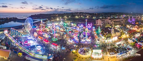 The San Diego County Fair at night, also called the Del Mar Fair, glows with many colorful lights and amusement rides at night in this aerial photo