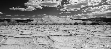 Arid and barren mud flats, dried mud, with the tall Eureka Dunes in the distance, Eureka Valley, Death Valley National Park, California