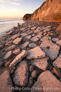 Remains of the old historic "Coast Highway 101", undermined as the bluff upon which it was built eroded away, now broken into pieces of concrete and asphalt blocks and fallen down the sea cliffs, lying on the beach, Carlsbad, California