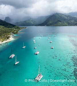 Cruising Sailboats at anchor in lagoon, Moorea, French Polynesia, aerial view. Opunohu Bay in the distance