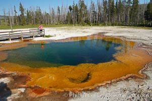 A visitor photographs Emerald Pool, Black Sand Basin, Yellowstone National Park, Wyoming