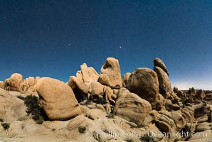 Joshua Tree National Park boulders under a night sky and stars.  Mars is visible in the middle of the image