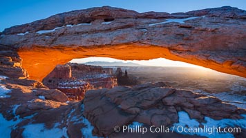 Mesa Arch spans 90 feet and stands at the edge of a mesa precipice thousands of feet above the Colorado River gorge. For a few moments at sunrise the underside of the arch glows dramatically red and orange, Island in the Sky, Canyonlands National Park, Utah