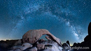 The Milky Way galaxy arcs above Arch Rock, panoramic photograph, cylindrical projection, Joshua Tree National Park, California