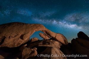 The Milky Way stretches across the sky above Arch Rock in Joshua Tree National Park