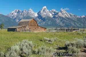 An old barn at Mormon Row is lit by the morning sun with the Teton Range rising in the distance, Grand Teton National Park, Wyoming