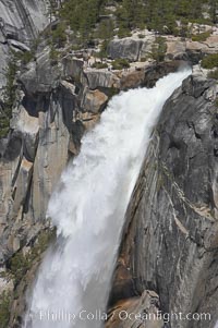 The brink of Nevada Falls, with hikers visible at the precipice. Nevada Falls marks where the Merced River plummets almost 600 through a joint in the Little Yosemite Valley, shooting out from a sheer granite cliff and then down to a boulder pile far below, Yosemite National Park, California