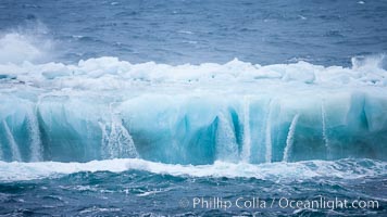 Ocean waves wash over a flat iceberg, carving gulleys into the sides of the iceberg, Scotia Sea