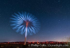 Stars rise above the Ocotillo Wind Turbine power generation facility, with a flashlight illuminating the turning turbine blades
