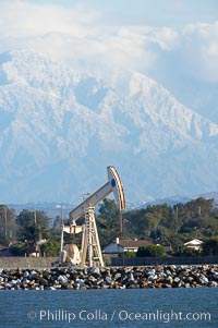 Oil pump, tract homes and snow-covered San Bernardino mountains, viewed from Bolsa Chica State Ecological Reserve, Huntington Beach, California