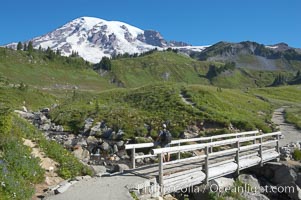 A hiker admires Mount Rainier from the footbridge crossing Edith Creek, Paradise Meadows, Mount Rainier National Park, Washington