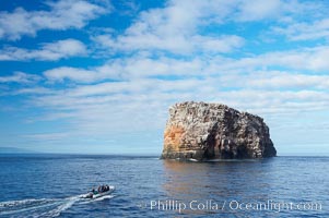 An inflatable boat full of adventurous divers heads towards Roca Redonda (round rock), a lonely island formed from volcanic forces, in the western part of the Galapagos archipelago