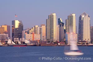 San Diego city skyline at dusk, viewed from Harbor Island, a sailboat cruises by in the foreground, the Star of India at left