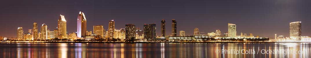 San Diego city skyline at night, showing the buildings of downtown San Diego reflected in the still waters of San Diego Harbor, viewed from Coronado Island.  A panoramic photograph, composite of five separate images
