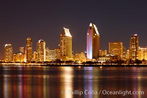 San Diego city skyline at night, showing the buildings of downtown San Diego reflected in the still waters of San Diego Harbor, viewed from Coronado Island