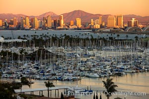 San Diego city skyline, showing the buildings of downtown San Diego rising above San Diego Harbor, viewed from Point Loma with the San Diego Yacht Club in the foreground, sunset