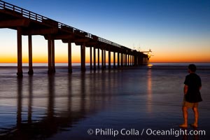 Guy watches the sunset over the SIO pier, the research pier at Scripps Institution of Oceanography SIO, La Jolla, California