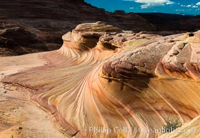 The Second Wave at sunset. The Second Wave, a curiously-shaped sandstone swirl, takes on rich warm tones and dramatic shadowed textures at sunset. Set in the North Coyote Buttes of Arizona and Utah, the Second Wave is characterized by striations revealing layers of sedimentary deposits, a visible historical record depicting eons of submarine geology, Paria Canyon-Vermilion Cliffs Wilderness