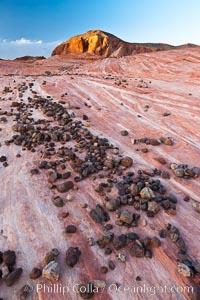 Stones, striated sandstone and sunset light on nearby butte, Valley of Fire State Park