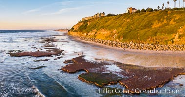 Swamis Beach Reefs Exposed by King Tides, people explore ocean reefs normally underwater but exposed on the extreme low tides known as King Tides. Aerial photo, Encinitas, California