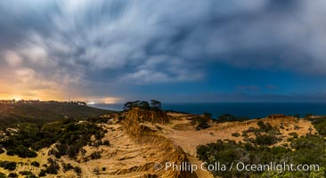 Torrey Pines State Reserve at Night, stars and clouds fill the night sky with the lights of La Jolla visible in the distance, San Diego, California