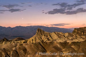 Venus sets over Manley Beacon and the Panamint Mountains, viewed from Zabriskie Point, landscape lit by a full moon, evening, stars, Death Valley National Park, California