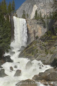 Vernal Falls and the Merced River, at peak flow in late spring.  Hikers ascending the Mist Trail visible at right.  Vernal Falls drops 317 through a joint in the narrow Little Yosemite Valley, Yosemite National Park, California