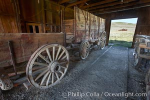 Wagon and interior of County Barn, Brown House and Moyle House in distance, Bodie State Historical Park, California
