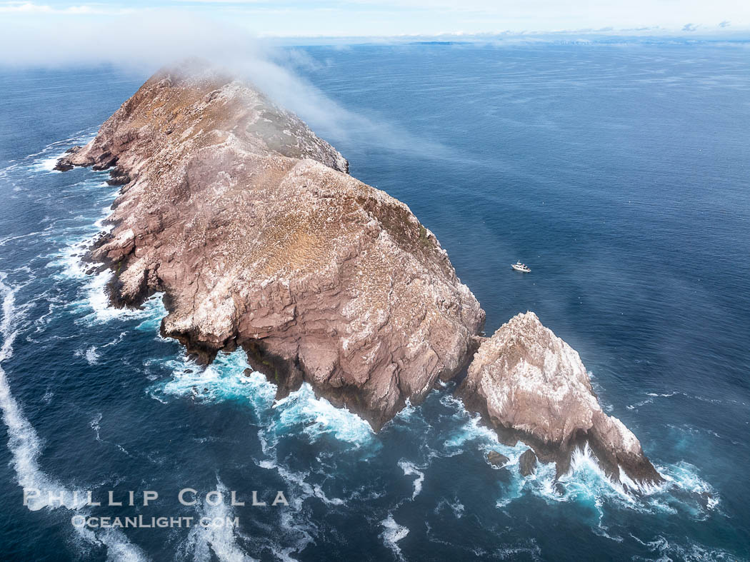 North Coronado Island, Mexico, southern point and keyhole looking north, clouds hugging the top of the island, San Diego in the distance, aerial photograph, Coronado Islands (Islas Coronado)