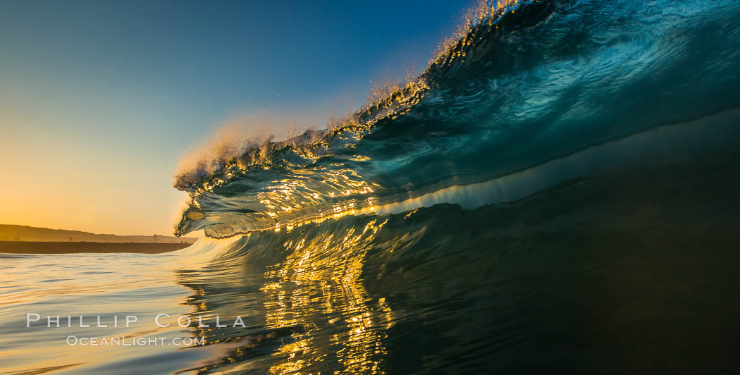 Sunrise glints yellow on breaking wave, dawn surf, The Wedge, Newport Beach, California